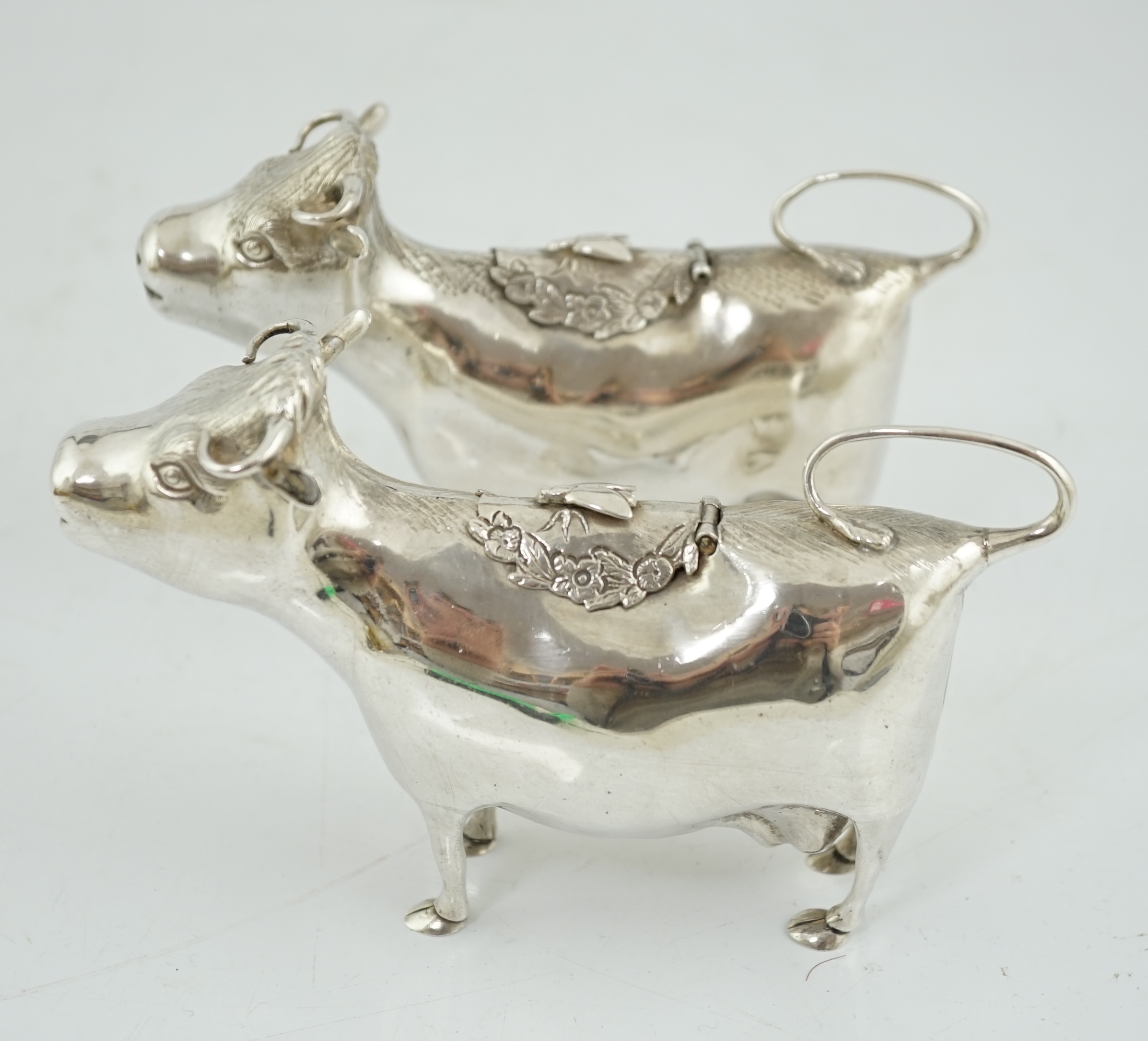 A pair of Elizabeth II silver cow creamers, by Heming & Co